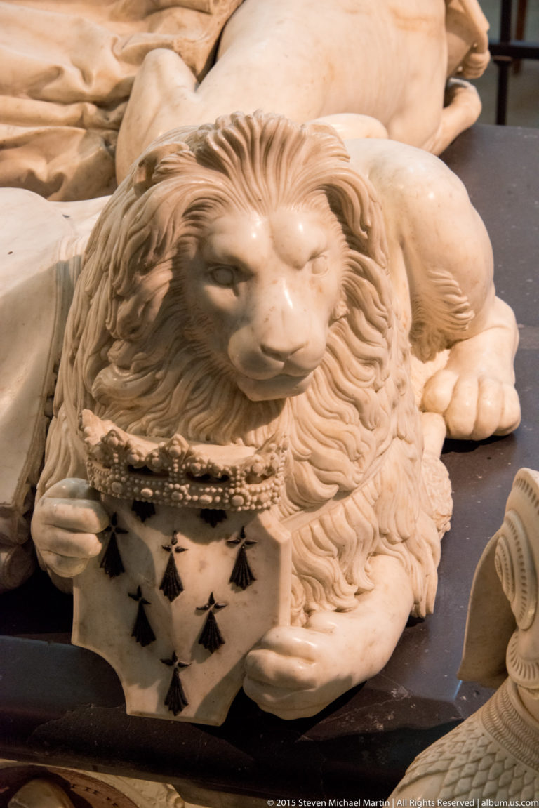Close view of a carved recumbent lion holding an ermine-patterned shield on the tomb of Francis II and Marguerite de Foix.