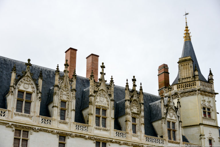 Ornate Gothic dormer windows and a slender turret with gilded finial rise above the château's steep slate roof.