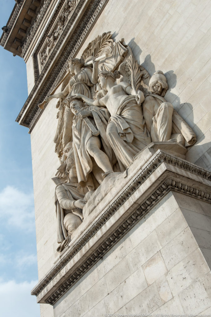 Low-angle close view of a monumental high-relief group by Antoine Étex projecting from a limestone pier of the Arc de Triomphe.