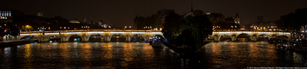 Pont Neuf crossing the Seine at night, with illuminated stone arches and warm lights reflected in the river.