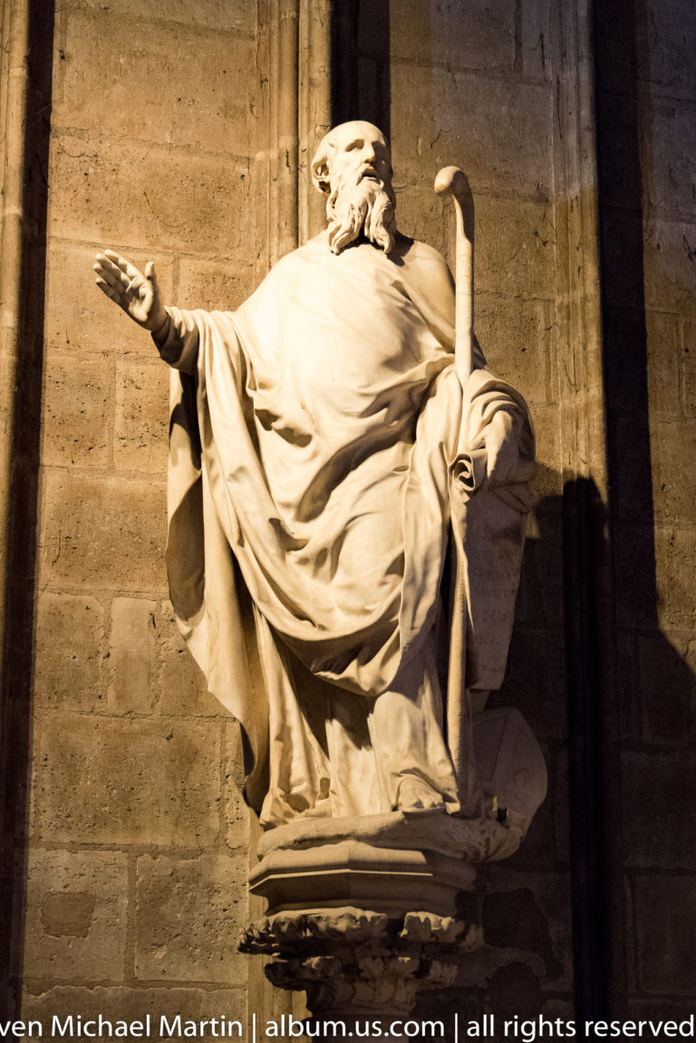 Seated sculpture of the biblical King David holding a harp inside Notre-Dame de Paris.