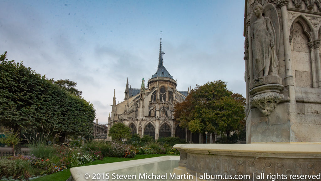Neo-Gothic Notre-Dame Fountain in Square Jean XXIII with the cathedral’s apse and spire behind.