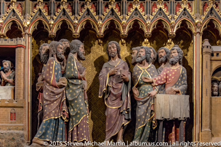 Risen Christ surrounded by apostles, one holding an open book, beneath gilded pointed arches.