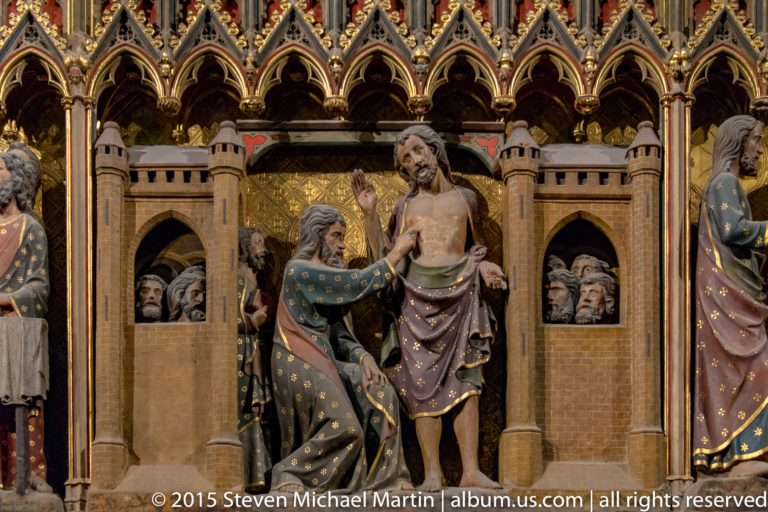 Christ shows the wound in his side to an apostle while other disciples watch from a painted architectural setting.