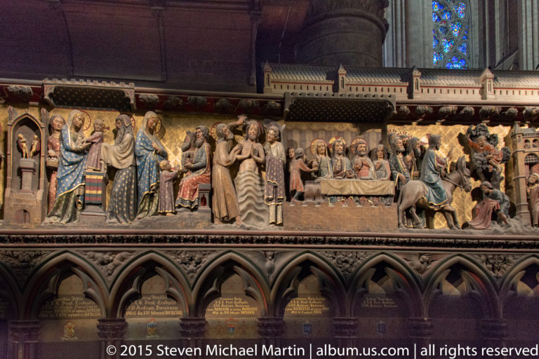 Long polychrome relief cycle with many biblical figures arranged in sequential scenes beneath Gothic arches.
