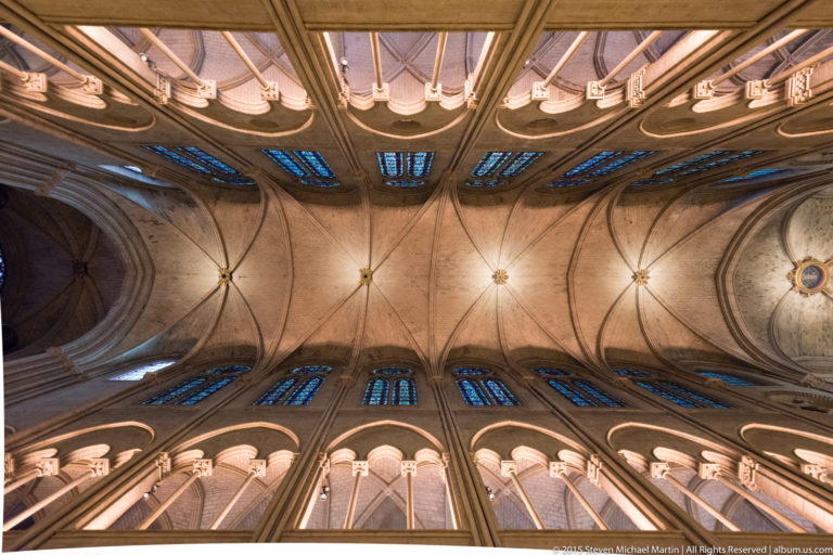 Upward view of repeating rib vaults and clerestory windows along both sides of the nave.