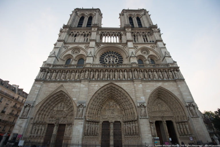 Low-angle west façade with three sculpted portals, Gallery of Kings, central rose window, upper gallery, and twin towers.