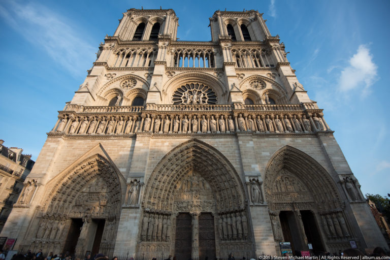 Low-angle frontal view of Notre-Dame’s west façade with three portals, Gallery of Kings, rose window, and twin towers.