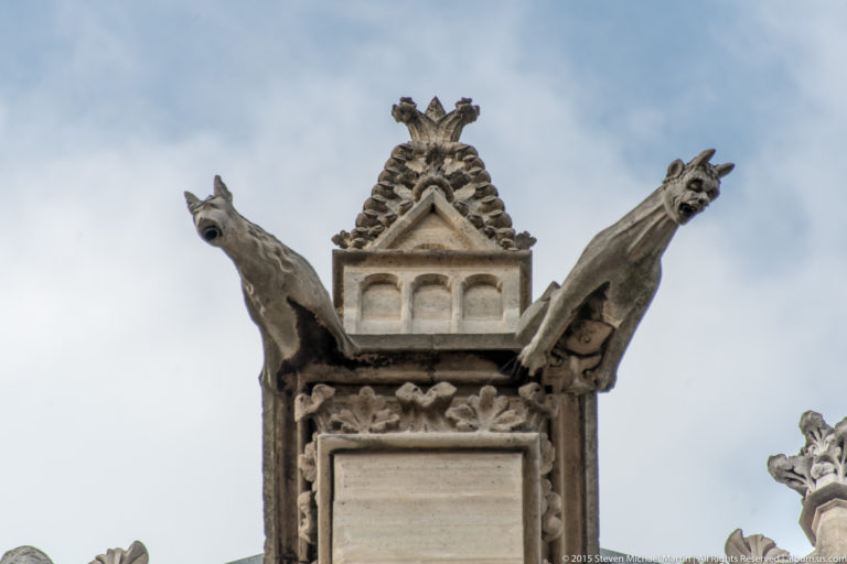 Close exterior view of a Sainte-Chapelle pinnacle with two projecting gargoyles and carved stone ornament.
