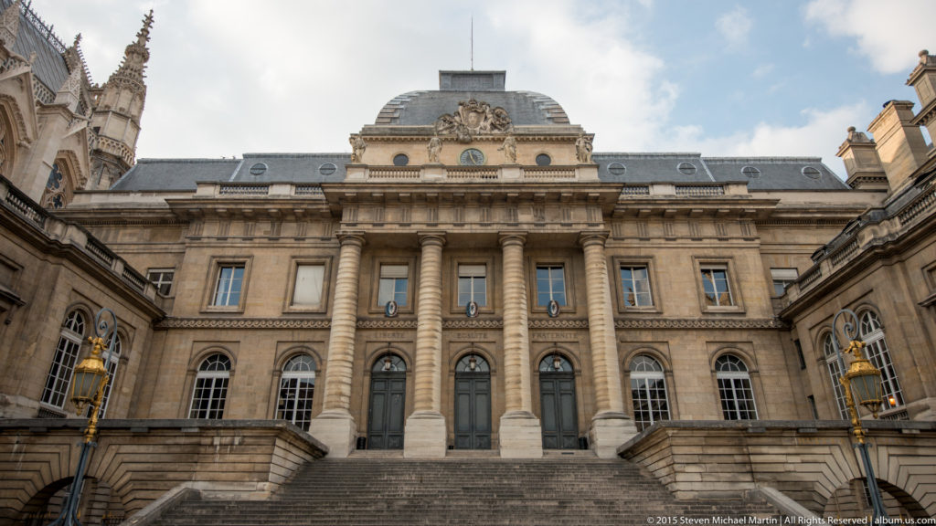 Formal stone façade and entrance steps of a Palais de Justice building in the Sainte-Chapelle complex on the Île de la Cité.