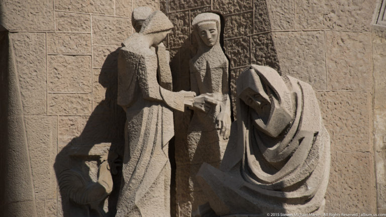 Close view of two angular stone figures by Josep Maria Subirachs on the Sagrada Família Passion façade.