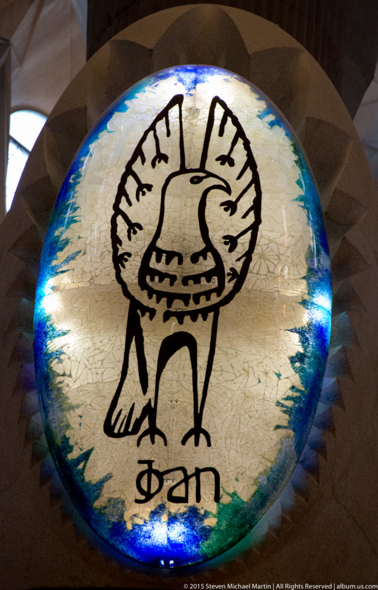 Blue-edged circular medallion with a stylized winged eagle and the Catalan name Joan.