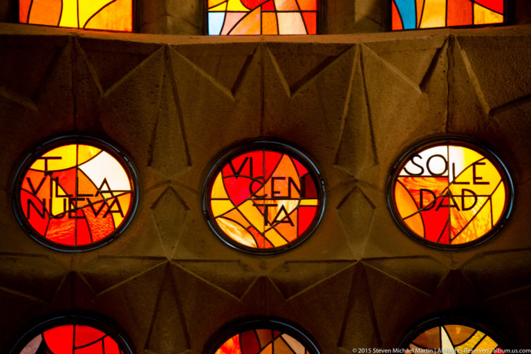 Three round red, orange, and yellow stained-glass windows with black lettering, including the word SOLEDAD.