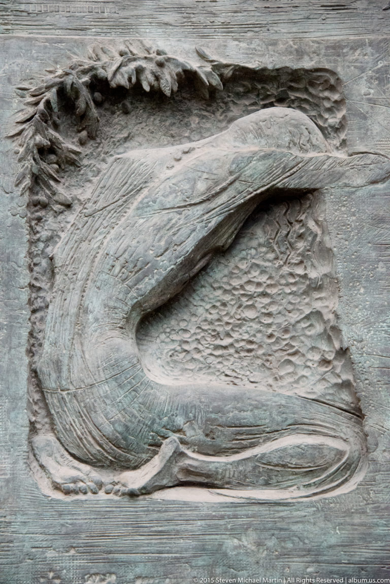 Coiled serpent relief beside the Kiss of Judas scene on the Sagrada Família Passion façade.