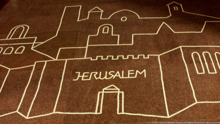 Linear outline of a walled city labeled JERUSALEM on a dark architectural surface at the Sagrada Família.