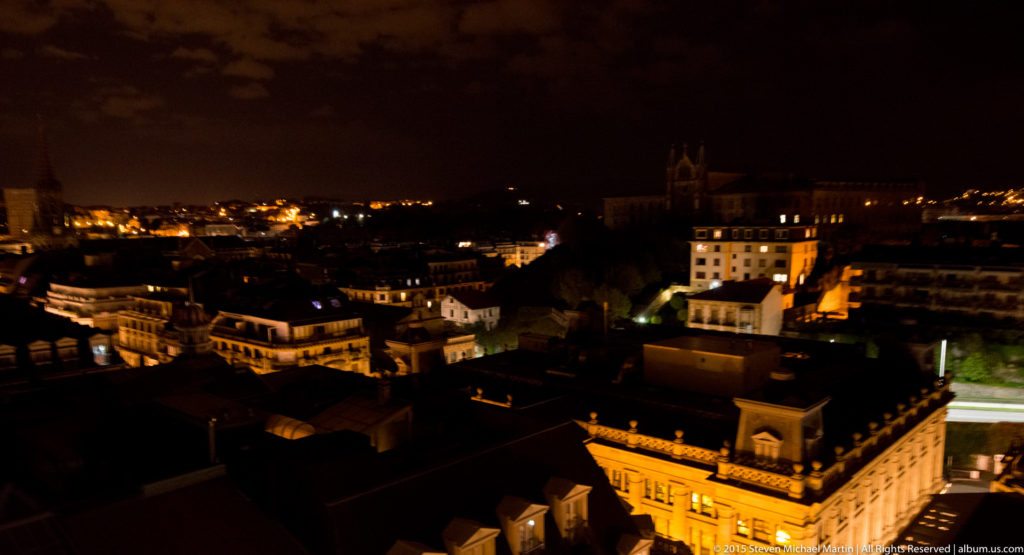 Dark San Sebastián skyline with a tall church tower rising above illuminated rooftops and streets.