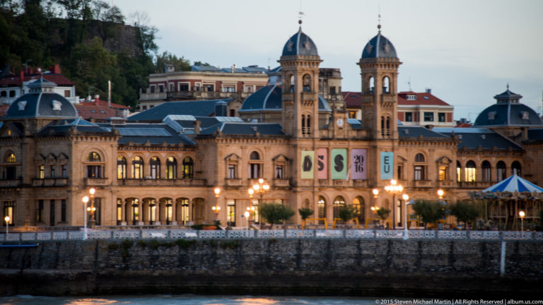 San Sebastián City Hall at dusk, with twin towers, domed roofs, arched windows, and illuminated stone façade.