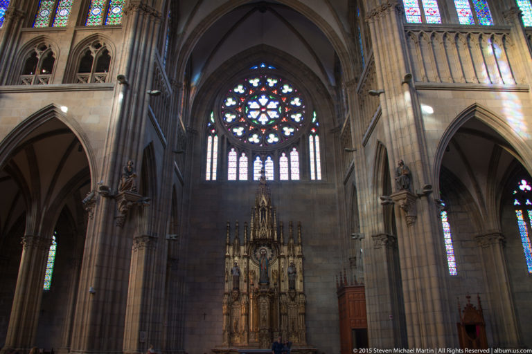 Buen Pastor Cathedral sanctuary with a large rose window, stained-glass lancets, pointed arches, and ornate central altar.