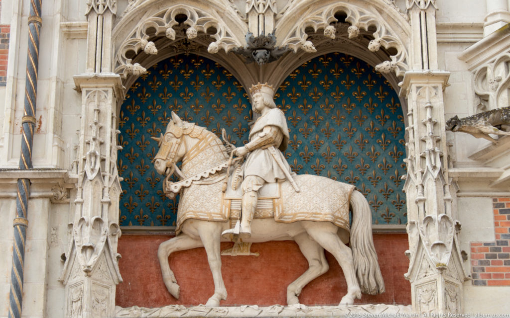 Equestrian statue of Louis XII beneath a carved canopy on a blue fleur-de-lis field at Blois château.