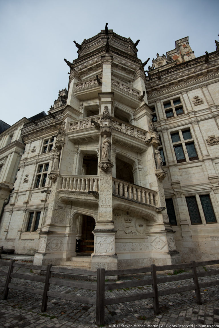 Low-angle view of the François I spiral stair tower with projecting balconies and elaborate carved stonework.
