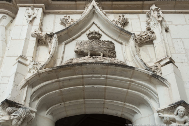 Crowned porcupine relief above a pointed stone arch with decorative Gothic carving at Blois château.