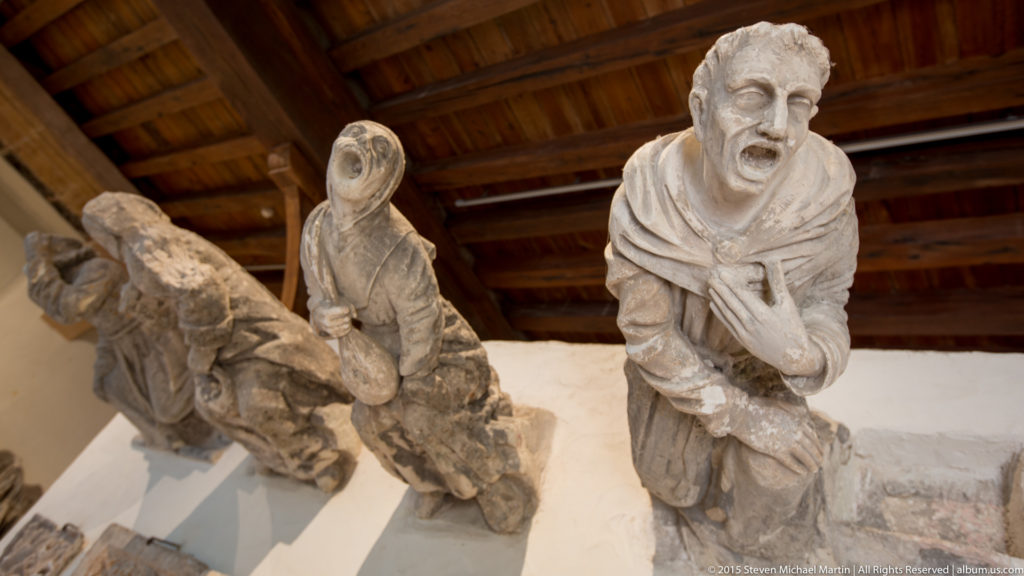 Close display of carved stone grotesques including a grimacing human figure and other sculptural fragments.