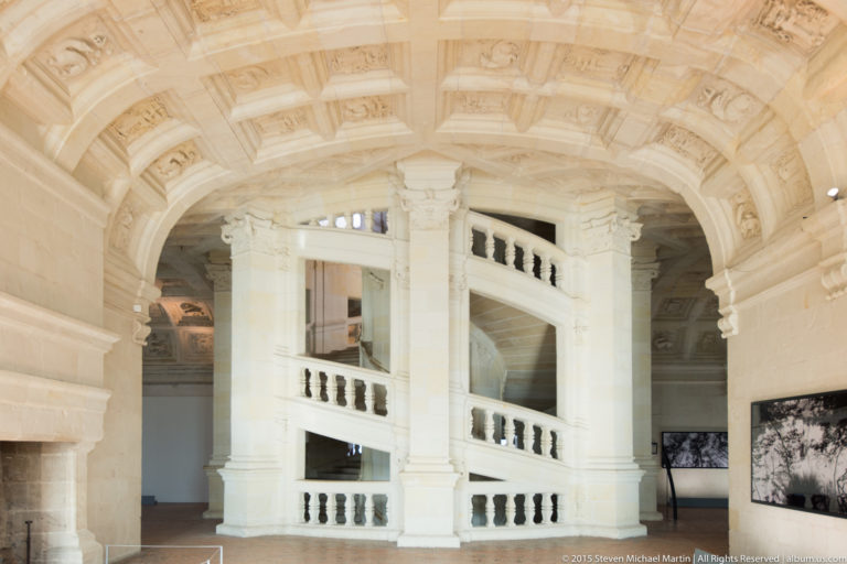 Interior landing of Château de Chambord’s double-helix staircase with broad curving flights, arches, and stone balustrades.