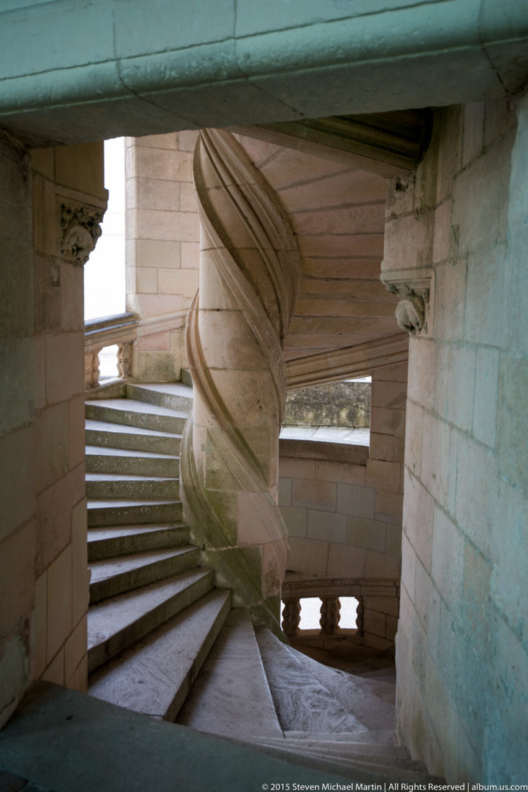 Close side view of twisting stone stair structure and adjacent steps within Château de Chambord’s double-helix staircase.