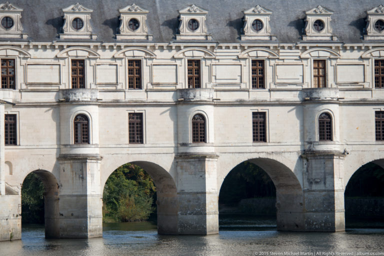 Close exterior view of Chenonceau’s long gallery, with pale stone façade and arches spanning the River Cher.