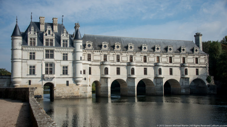 Broad view of Château de Chenonceau with turrets, dormers, and long arched gallery over the River Cher.