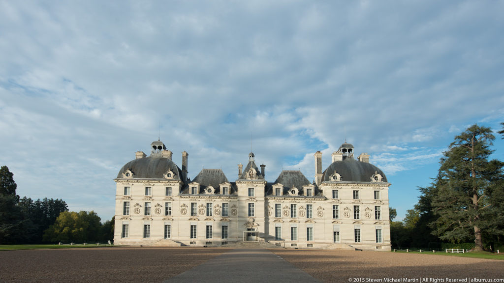 Château de Cheverny seen across a broad forecourt, with a symmetrical pale-stone façade, slate roofs, dormers, and corner pavilions.