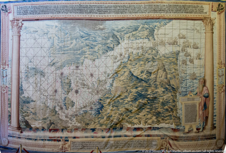 Woven map showing mountainous coastlines, islands, and intersecting navigation lines, framed by decorative borders and a standing figure.