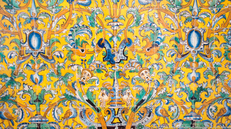 Close-up of multicolored glazed tiles with symmetrical scrolling foliage, fantastic creatures, urn forms, and oval medallions.