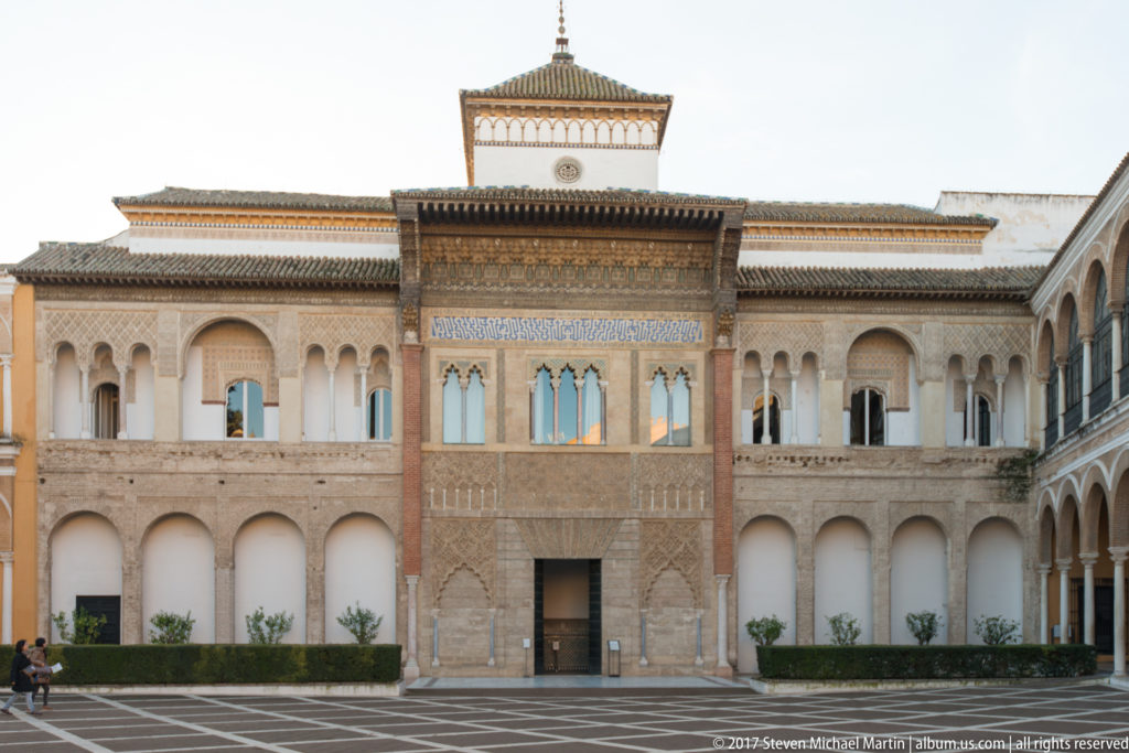 Ornate central façade of the Palace of Pedro I, with arcades, carved stucco, tilework, windows, and projecting timber eaves.