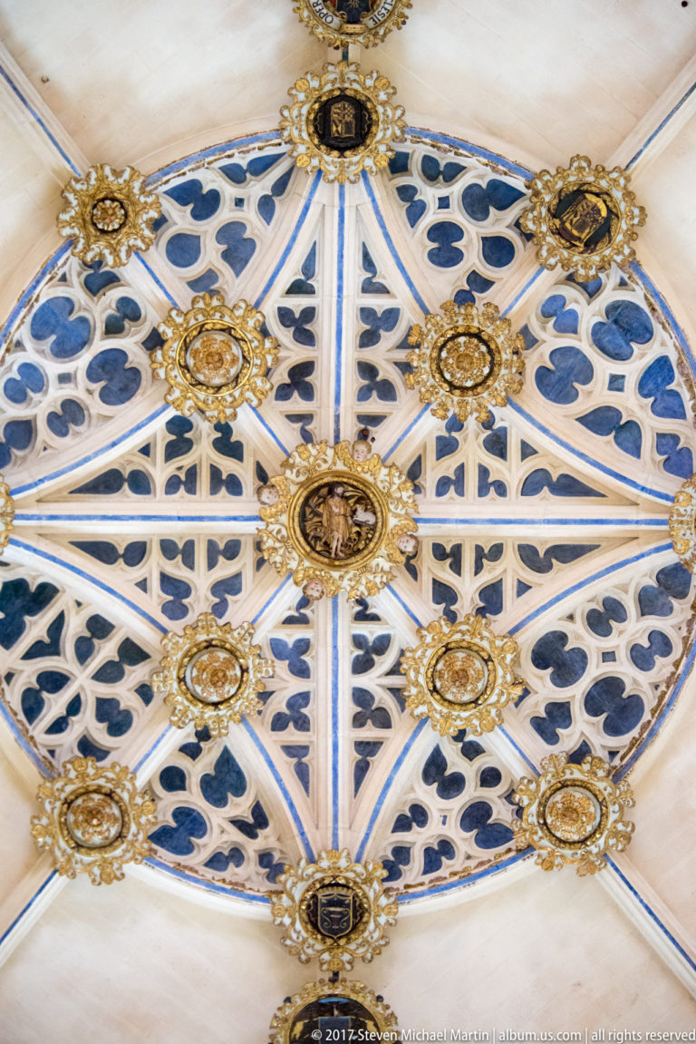 Blue-and-white patterned cathedral vault divided by pale ribs and decorated with numerous gilded circular bosses.