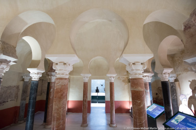 Rows of horseshoe arches and marble columns inside the reconstructed Caliphal Baths, with interpretive displays in the foreground.