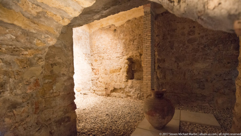 Large ceramic jar beside rough stone and brick walls in an excavated chamber of Córdoba’s Caliphal Baths.