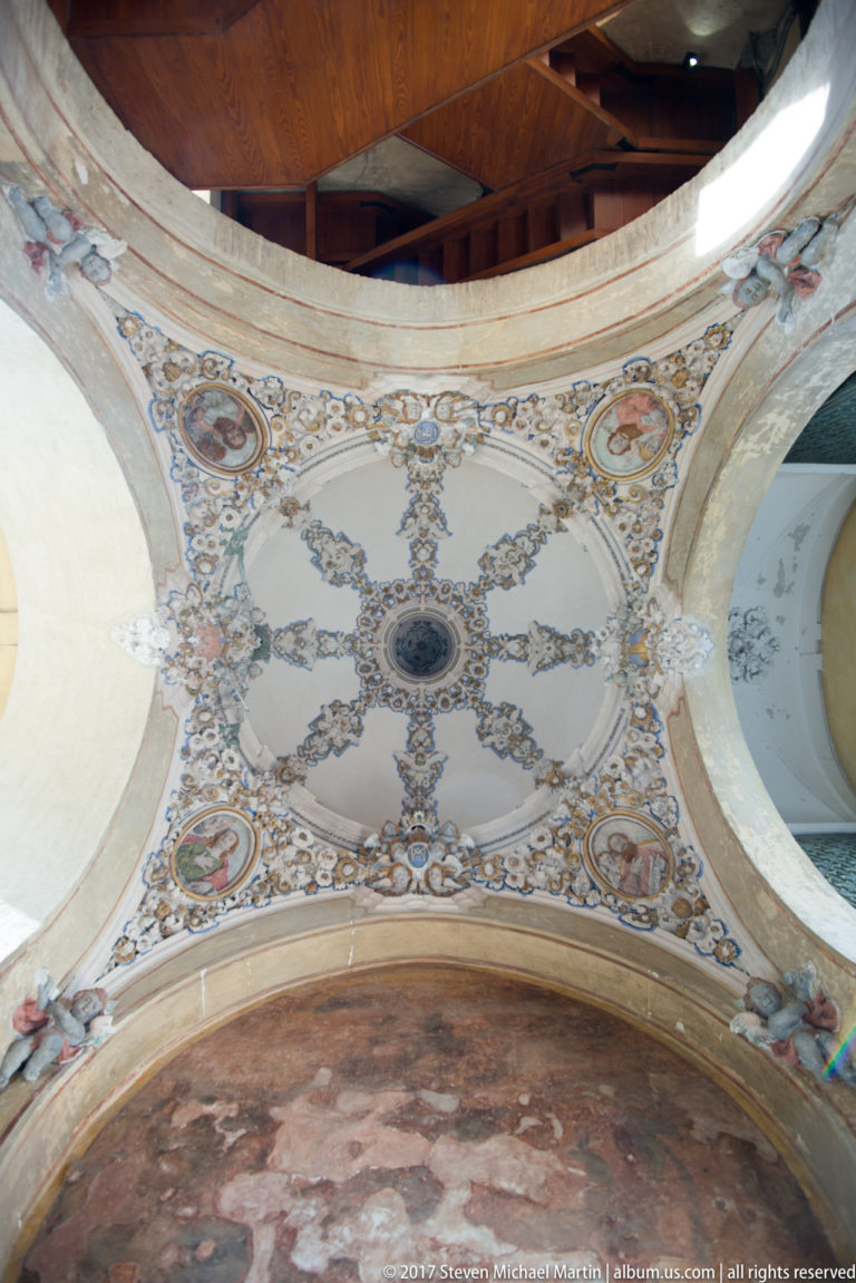 Ornate ceiling with gilded garlands, painted roundels, floral decoration, and a central circular medallion between arches.