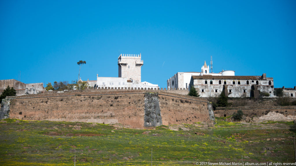 Estremoz Castle above massive stone walls, with pale crenellated keep and white palace buildings on the hilltop.