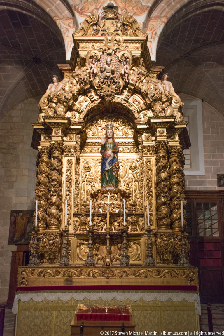 Gilded Baroque retable with twisting columns and dense carved ornament surrounding a central image of the Virgin.