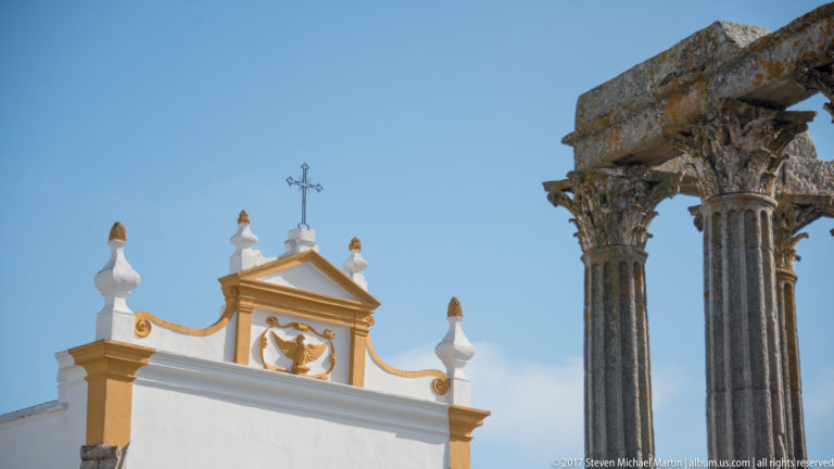 Roman Temple of Évora columns beside the white-and-ochre façade of the Igreja de São João Evangelista, or Igreja dos Lóios.