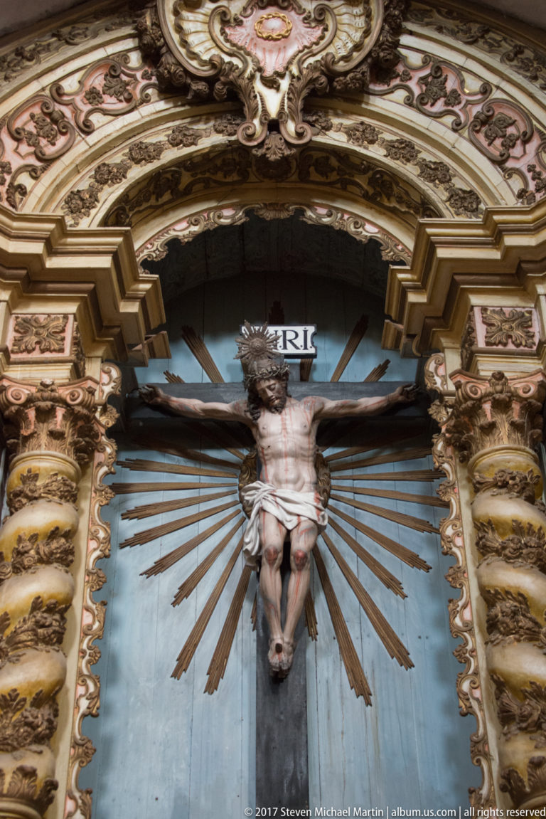Crucifix with radiating rays and gilded carved surround inside the Igreja de São Francisco in Évora.