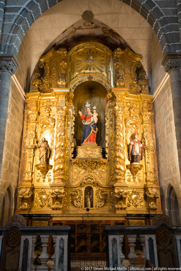 Gilded Baroque altarpiece with twisting columns, saint figures, central Marian scene, and multicolored altar frontal in the Igreja de São Francisco complex in Évora.
