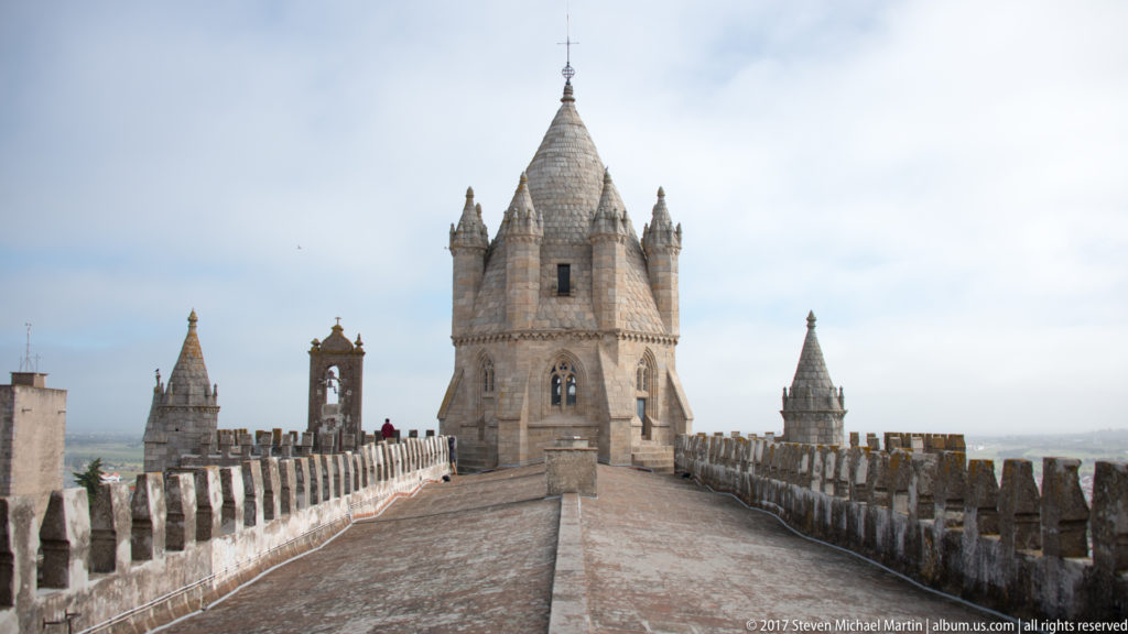 Crenellated rooftop walkway at Évora Cathedral leading straight toward the large polygonal central tower.