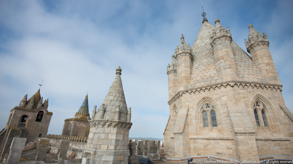 Cluster of Évora Cathedral towers, including the large turreted polygonal tower, a conical pinnacle, and square bell tower.