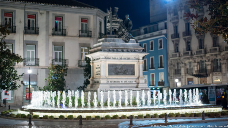Illuminated monument to Isabella I and Christopher Columbus above fountain jets in Plaza de Isabel la Católica, Granada.