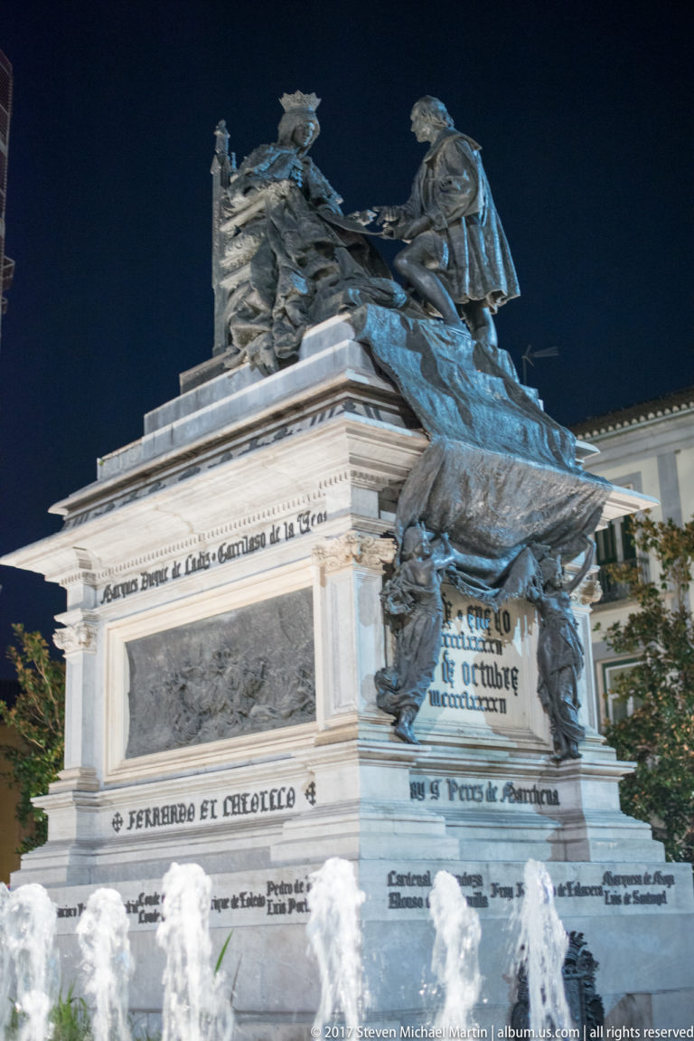 Night view of the Isabella I and Christopher Columbus monument on an inscribed stone pedestal in Granada.
