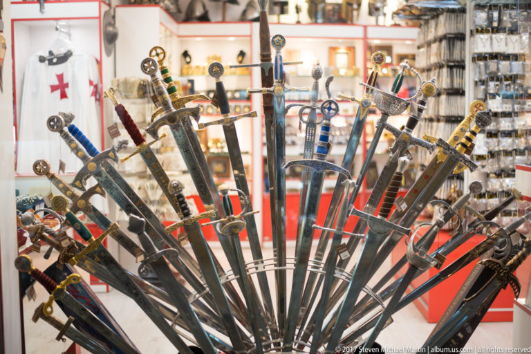Fan-shaped rack of decorative swords with varied hilts inside a Granada souvenir shop.