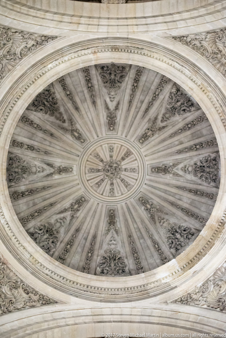 Close upward view of a circular stone vault with radial ribs and carved ornament in Granada Cathedral.