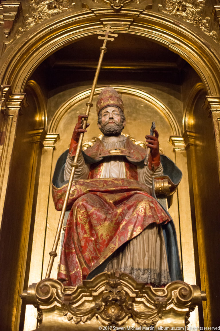 Polychrome seated Saint James the Greater holding a pilgrim staff in a gilded niche in Granada Cathedral.